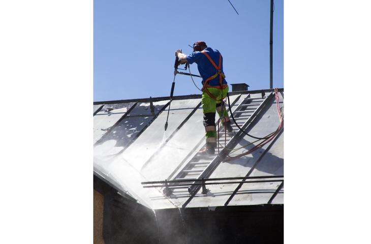 Homme nettoyant à haute pression un toit