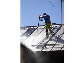 Homme nettoyant à haute pression un toit